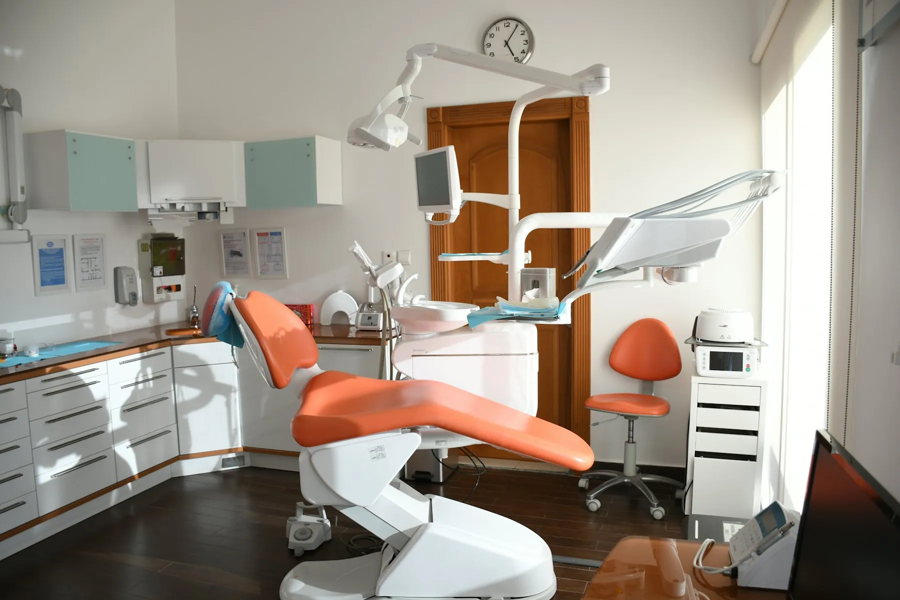 A calm treatment room with an orange chair and wood door